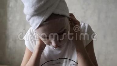 戴着<strong>保湿面膜</strong>的白种人女人头上结了一条白色毛巾，看着相机。 清洁